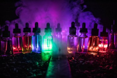 Vape kavramı. Sisli bir gecede dev cam şişe ile yolun ortasında duran bir adam silüeti elektronik sigara sıvı ile dolu. Işık arka plan üzerinde renkli sisli bulutlar.