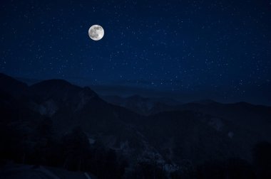 Dağ yolu ormandaki bir dolunay gecesi. Ülke yolun gece büyük moon ile doğal gece manzarası