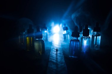 Vape kavramı. Sisli bir gecede dev cam şişe ile yolun ortasında duran bir adam silüeti elektronik sigara sıvı ile dolu. Işık arka plan üzerinde renkli sisli bulutlar.