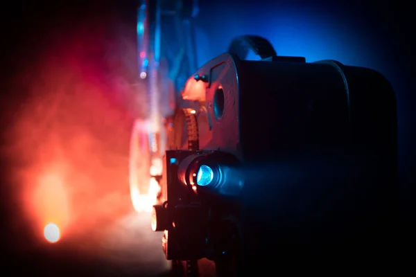 Old vintage movie projector on a dark background with fog and light. Concept of film-making. Selective focus