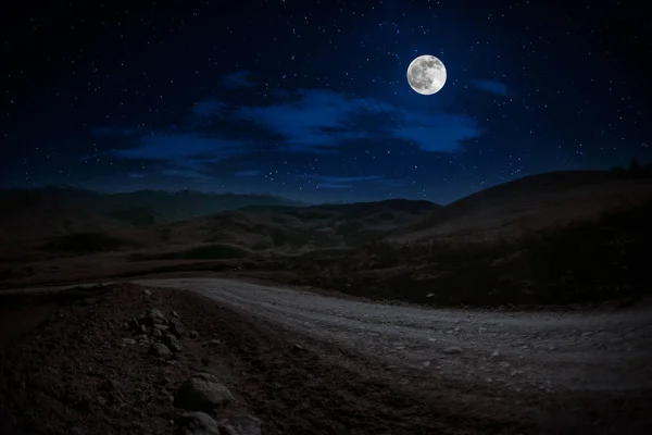 Mountain Road attraverso la foresta in una notte di luna piena. Paesaggio paesaggistico notturno di strada di campagna di notte con grande luna. Tapparella lunga foto — Foto Stock