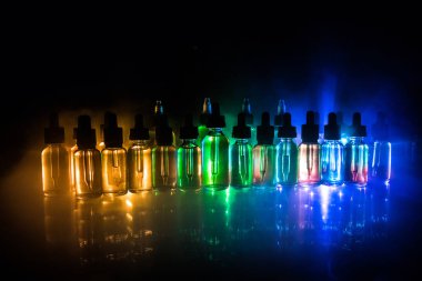 Vape kavramı. Duman bulutları ve vape sıvı şişe koyu arka plan üzerinde. Işık efektleri. Arka plan veya elektronik sigara reklam olarak kullanışlıdır. Seçici odak