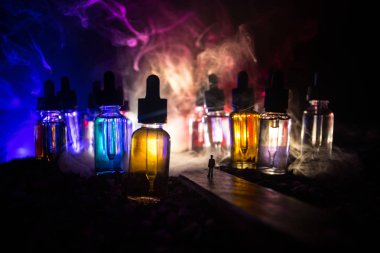 Vape kavramı. Sisli bir gecede dev cam şişe ile yolun ortasında duran bir adam silüeti elektronik sigara sıvı ile dolu. Işık arka plan üzerinde renkli sisli bulutlar.