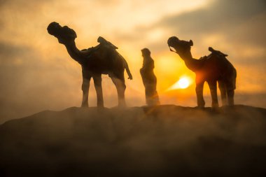 Deve kervan günbatımında çölde kum tepeleri geçmekte. Eastern Seyahat kavramı. Resim dekorasyon