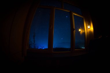 Gece sahne yıldız karanlık oda gelen pencereden gördüm. Gece gökyüzü karanlık odada eski vintage fenerle penceresinden ile ilgilenen. Uzun pozlama vurdu