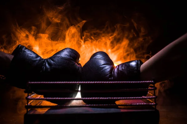 Empty boxing ring with red ropes for match in the stadium arena. Boxing gloves ready to fight. Empty space for text. Foggy background with light. Selective focus