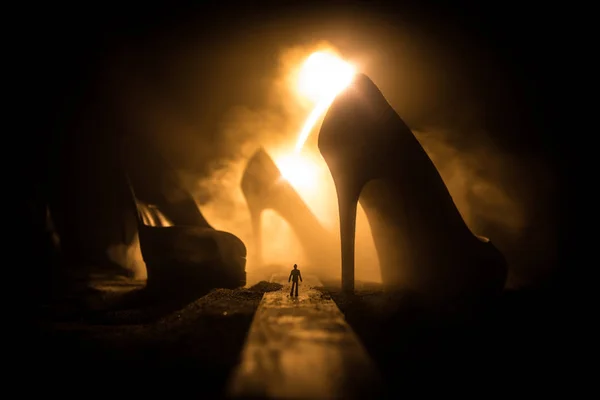 アートワークの装飾 巨大なハイヒールの女性の靴と霧の夜に道の真ん中に立っている人のシルエット 女性のパワーや女性支配概念 選択と集中 — ストック写真