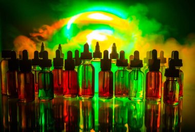 Vape kavramı. Duman bulutları ve vape sıvı şişe koyu arka plan üzerinde. Işık efektleri. Arka plan veya elektronik sigara reklam olarak kullanışlıdır. Seçici odak