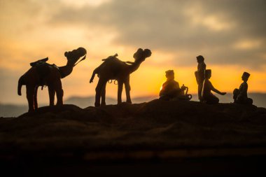 Deve kervan günbatımında çölde kum tepeleri geçmekte. Eastern Seyahat kavramı. Resim dekorasyon