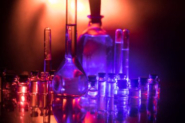 Eczane ve kimya teması. Araştırma laboratuarında çözeltisi olan cam deney şişesi. Bilim ve tıbbi geçmiş. Koyu renk arkaplan üzerinde laboratuvar test tüpleri, bilimsel araştırma ekipmanları konsepti