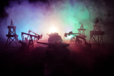 Resim dekorasyon. Petrol savaş kavramı. Askeri siluetleri, pompalar ve kulelerimiz petrol sahası. Puslu renkli gökyüzü arka plan. Zırhlı araçlar mücadele sahne. Seçici odak