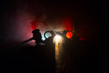 Hukuk hukuku ya da suç kavramı. Sisli bir gecede yolun ortasında tek başına duran bir adam. Kelepçeli sanat dekorasyonu, Adalet Heykeli ve sisli arka planda adalet tokmağı..