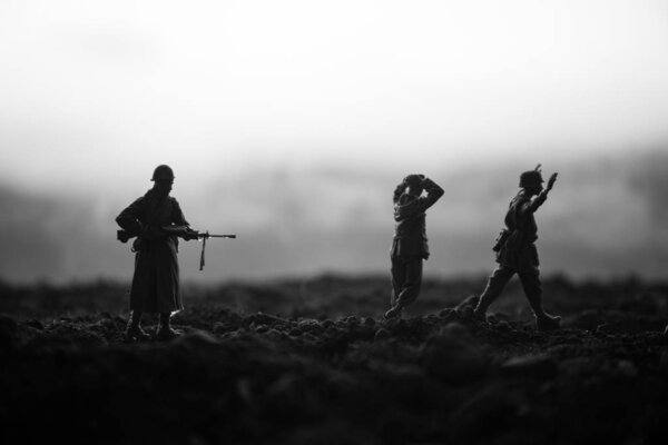 Battle scene. Military silhouettes fighting scene on war fog sky background. A German soldiers raised arms to surrender. Plastic toy soldiers with guns taking prisoner the enemy soldier. Artwork