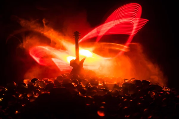 Music concept. Acoustic guitar on a dark background under beam of light with smoke. Emptry space for text. Fire effects. Surreal guitar