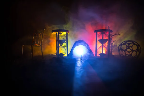 時間の概念 煙と暗い背景にライトと砂時計の間に立っている男のシルエット 超現実的な装飾写真 — ストック写真