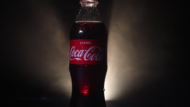 Baku, Azerbejdżan 13 stycznia 2018, klasyczne Coca-Cola w butelce szklanej na ciemnym stonowanych mglisty tło. Coca Cola jest najbardziej popularnych napojów gazowanych napojów bezalkoholowych sprzedawane na świecie — Wideo stockowe