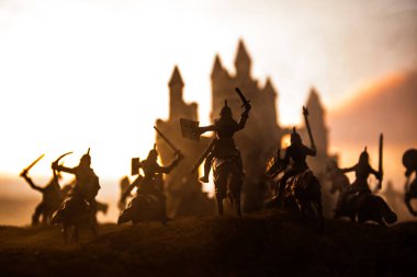 Süvari ve piyade ile Ortaçağ savaş sahnesi. Ayrı nesneler olarak figürlerin siluetleri, gün batımı sisli arka plan üzerinde savaşçılar arasında mücadele.