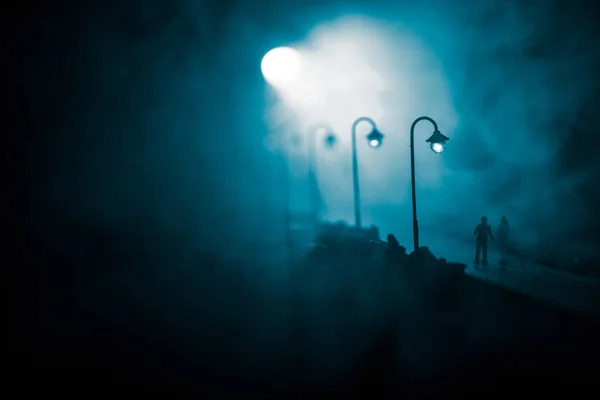 Casal jovem segurando as mãos um do outro. Caminhando lentamente sob luzes brancas de rua durante a noite. Tempo negro. Atmosfera pacífica em névoa. Ar enevoado . — Fotografia de Stock