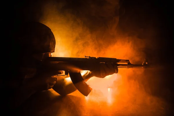 アサルトライフルの暗いトーンの霧の背景または危険な山賊の手に銃を保持している攻撃する準備を持つ男のシルエット 武器のテーマの装飾が施されたテロリストを撮影 — ストック写真