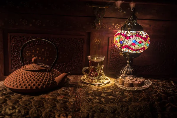 阿拉伯茶在玻璃与东方小吃在老式的木制表面 东方茶的概念 低浅色的休息室内饰 配有地毯 空的空间 选择性对焦 — 图库照片