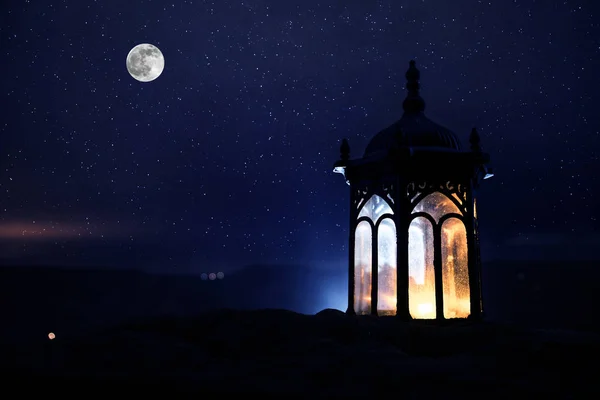 Ozdobná arabská lucerna s hořící svíčkou zářící v noci. Slavnostní přání, pozvánka pro muslimský svatý měsíc ramadán Kareem. — Stock fotografie