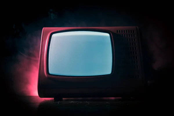 Old vintage red TV with white noise on dark toned foggy background. Retro old Television reciever no signal. Selective focus