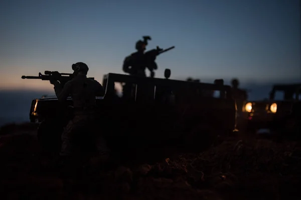 Conceito de Guerra. Silhuetas militares lutando cena no fundo do céu de nevoeiro de guerra, silhuetas de combate Abaixo do Skyline Nublado À noite. Cena de batalha. Veículo do exército com soldados. exército — Fotografia de Stock