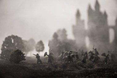 Süvari ve piyade ile Ortaçağ savaş sahnesi. Ayrı nesneler olarak figürlerin siluetleri, gün batımı sisli arka plan üzerinde savaşçılar arasında mücadele.