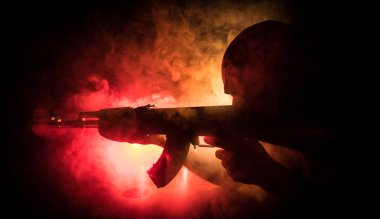 Saldırı tüfeği ile adam siluet ilerlemiş sisli arka plan veya elinde silah tutan tehlikeli haydut saldırmaya hazır.