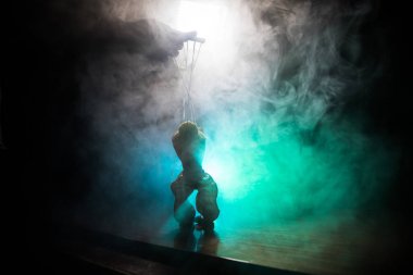 Manipülasyon kavramı. El manipülasyon için dizeleri tutar. El karanlık sisli bir arka plan üzerinde kukla dizeleri kontrol eder.