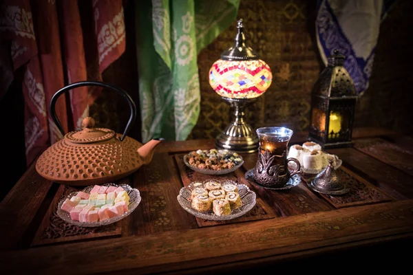 Arabische thee in glas met oosterse hapjes op Vintage houten oppervlak. Oosterse thee concept. Weinig licht lounge interieur met tapijt. Lege ruimte. — Stockfoto