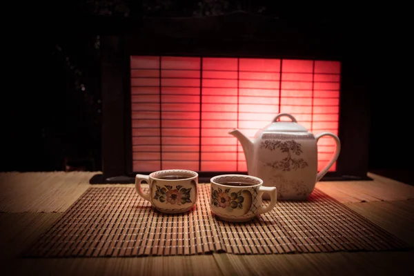 お茶のコンセプト。日本の茶道文化東飲料。夕日に竹の葉が入ったテーブルのティーポットとカップ — ストック写真