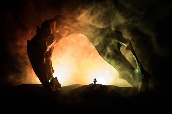 Decorazione d'arte con osso animale. Silhouette in una cripta sotterranea abbandonata. uomo in piedi davanti all'ingresso di una grotta — Foto Stock