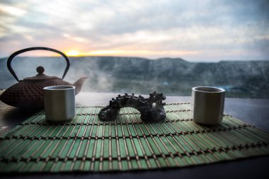 Çay konsepti. Japon çay töreni kültür doğu içecek. Gün batımında bambu yaprakları ile masada çaydanlık ve bardak