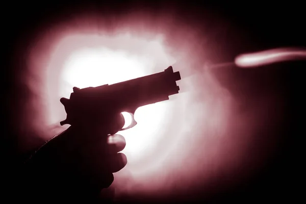 Чоловіча рука тримає пістолет на чорному тлі з димом тоновані задні ліхтарі — стокове фото