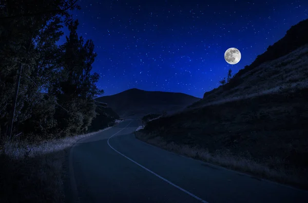 Bergsvägen genom skogen på en fullmåne natt. Natursköna Nattlandskap av landsväg på natten med stor Moon. Lång slutarbild — Stockfoto