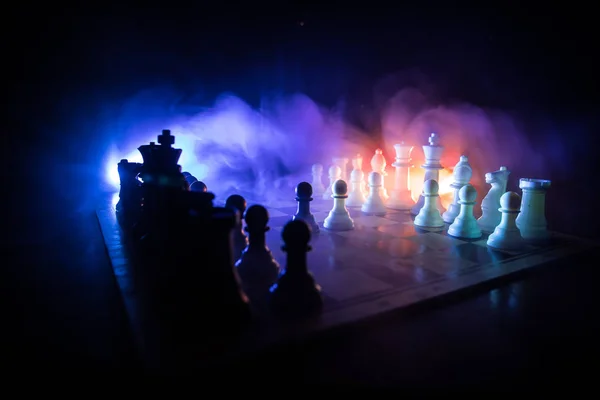Schaakbord spel concept van Business ideeën en competitie. Schaak figuren op een donkere achtergrond met rook en mist. — Stockfoto