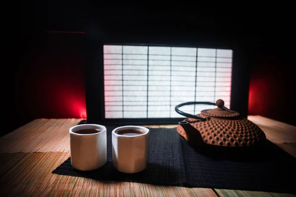 Tea concept. Japanese tea ceremony culture east beverage. Teapot and cups on table with bamboo leaves on sunset — Stock Photo, Image