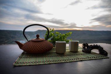 Çay konsepti. Japon çay töreni kültür doğu içecek. Gün batımında bambu yaprakları ile masada çaydanlık ve bardak