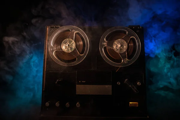 Old vintage reel to reel player and recorder on dark toned foggy background. Analog Stereo Open Reel Tape Deck Recorder Player with Reels. Selective focus