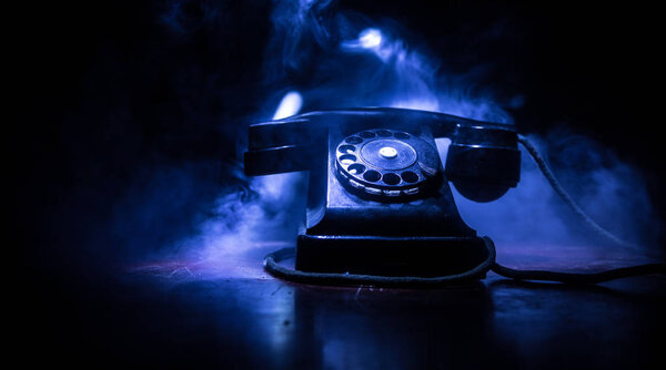 старый черный телефон на старой деревянной доске с искусством темного фона с туманом и тонированным светом. пустое место. Селективный фокус
