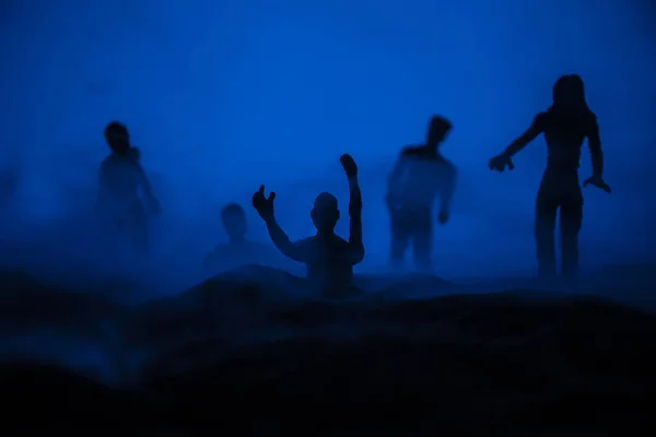 Horror Halloween concept. Silhouettes of scary zombies on misty field walking at the evening. Selective focus. Creative artwork decoration