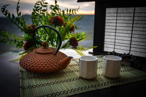 Thee concept. Japanse theeceremonie cultuur Oost drank. Theepot en kopjes op tafel met bamboe bladeren op zonsondergang — Stockfoto