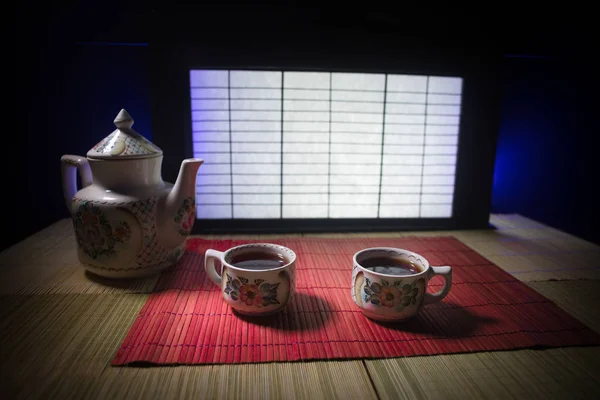 Tea concept. Japanese tea ceremony culture east beverage. Teapot and cups on table with bamboo leaves on sunset — Stock Photo, Image