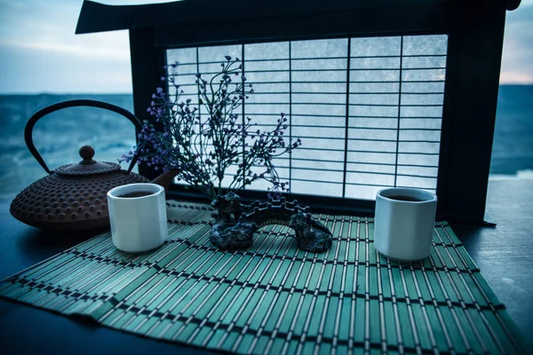 Tea concept. Japanese tea ceremony culture east beverage. Teapot and cups on table with bamboo leaves on sunset — Stock Photo, Image