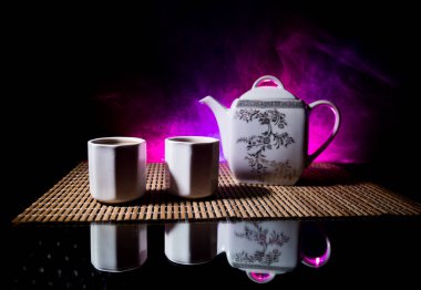 Çay konsepti. Japon çay töreni kültür doğu içecek. Gün batımında bambu yaprakları ile masada çaydanlık ve bardak