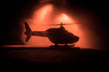 Askeri helikopter çatışma bölgesinden uçmaya hazır silüeti. Gece görüntüleri çöl sisli tonda sırt ile başlayarak helikopter ile dekore edilmiştir. Seçici odak.
