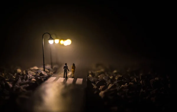 Pareja joven tomándose de las manos. Caminando lentamente bajo las luces blancas de la calle en la noche. Hora oscura. Ambiente pacífico en la niebla. Aire brumoso . — Foto de Stock