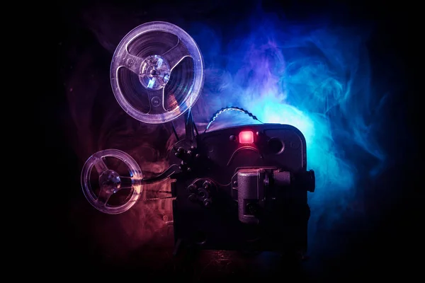 Oude vintage film projector op een donkere achtergrond met mist en licht. Concept van het maken van films. — Stockfoto