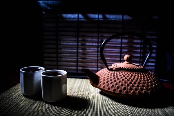 Tea concept. Japanese tea ceremony culture east beverage. Teapot and cups on table with bamboo leaves on sunset — Stock Photo, Image